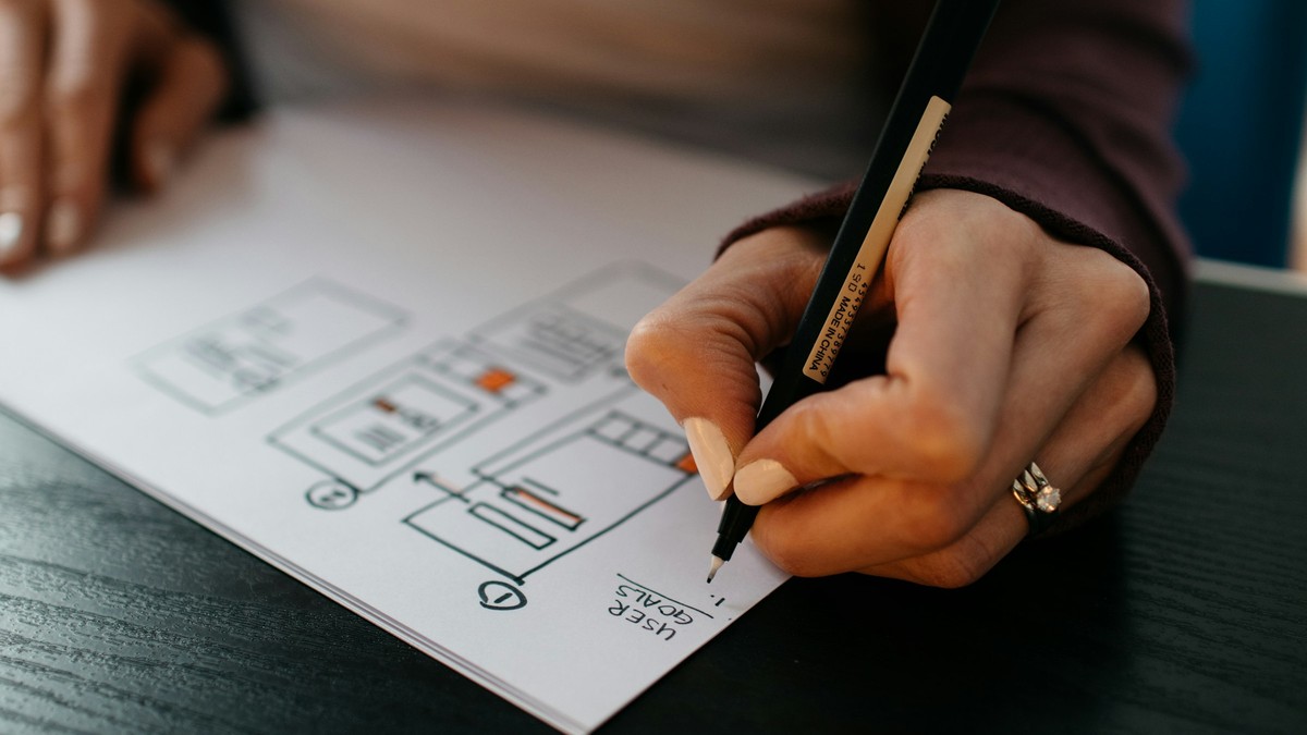 Hand sketching wireframes on white paper for a Figma AI agent credits try-or-skip decision