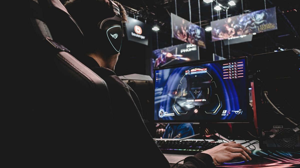 Gamer in a headset at a dark gaming setup for a Modern Warfare 4 PS5 pre-order decision