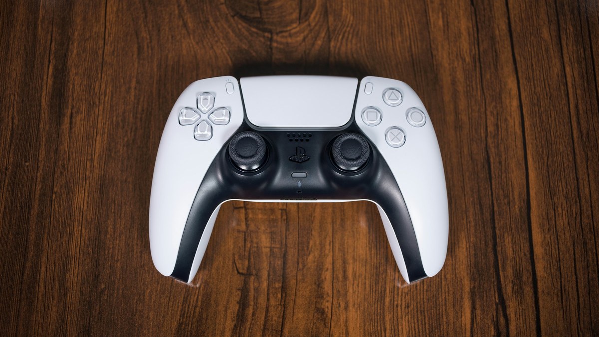 featured White game controller on a wooden table for a PS5 firmware 14.10 update guide