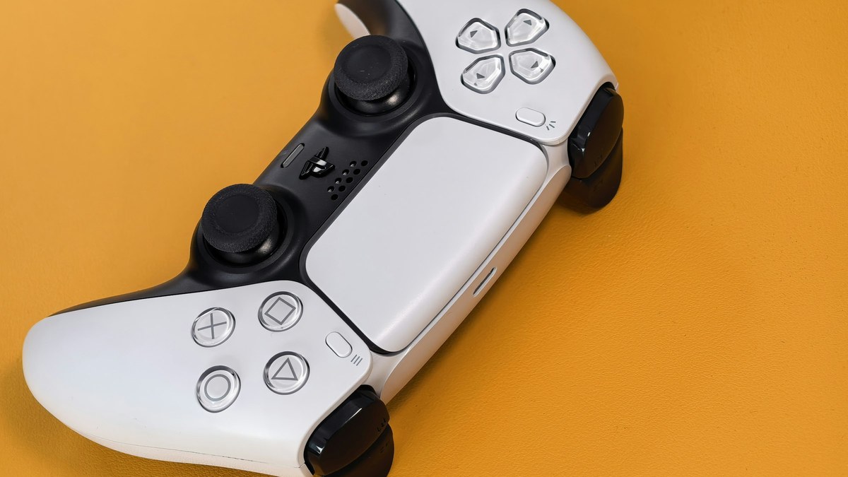 featured White game controller on an orange background for an explainer on owning PS5 digital games